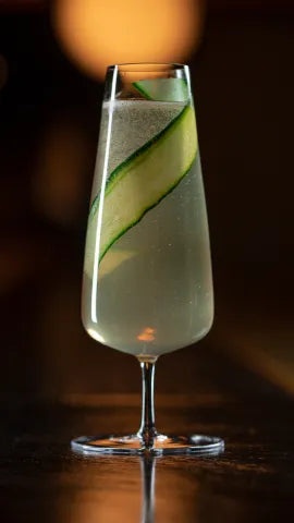 Axia Greek Mastiha Spirit and Oriole Bar Champagne Cocktail with cucumber on a wooden counter