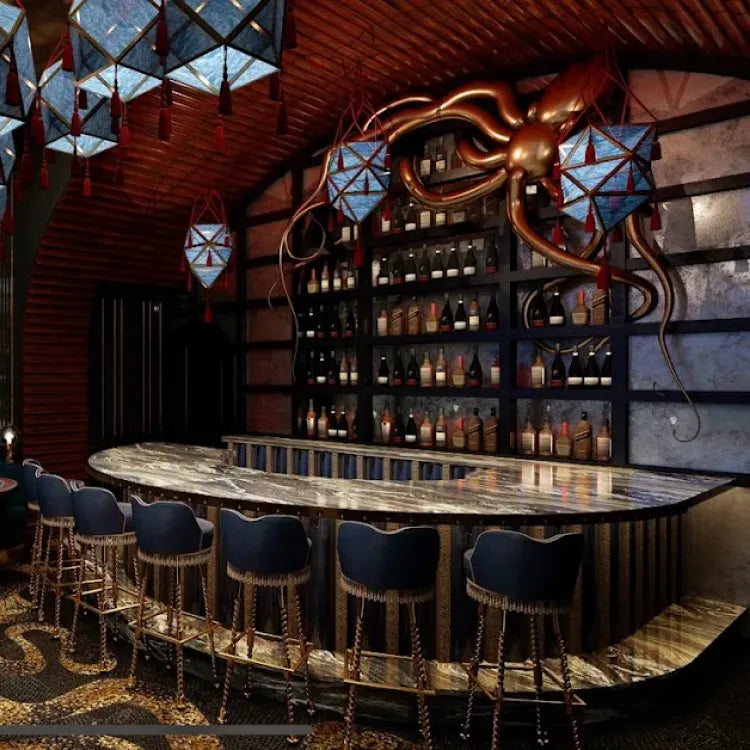 Shinjin's, New York: uniquely decorated bar with a curved, patterned countertop, plush blue bar stools, and shelves displaying bottles under an ornate, octopus-like sculpture with geometric lanterns above