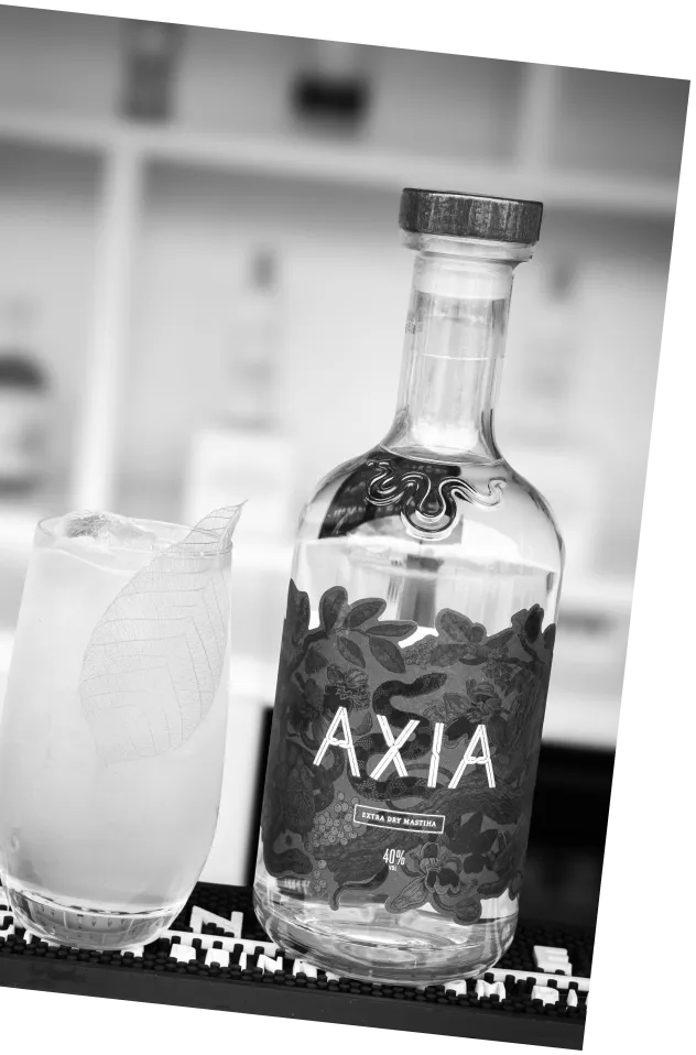 Black and white picture of a bottle of Axia Spirit next to a Yamas cocktail on a bar