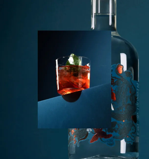 Axia Mediterranean Negroni Cocktail on a dark blue background with Axia Mastiha Spirit in the background as a second picture