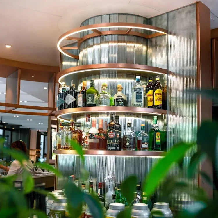 Mada One, Monaco: modern bar display with shelves of assorted liquor bottles, highlighted by circular lighting and metallic accents
