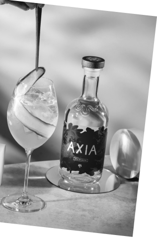 Black and white picture of an Axia and Gaucho Watermelon Spritz cocktail next to an Axia Mastiha Spirit bottle
