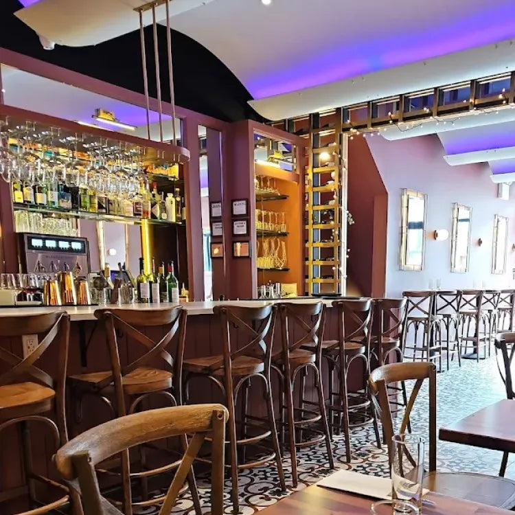 Tootles & French, New York: warmly lit, stylish bar area with a white countertop, wooden bar stools, an array of glasses hanging above and patterned floor tiles