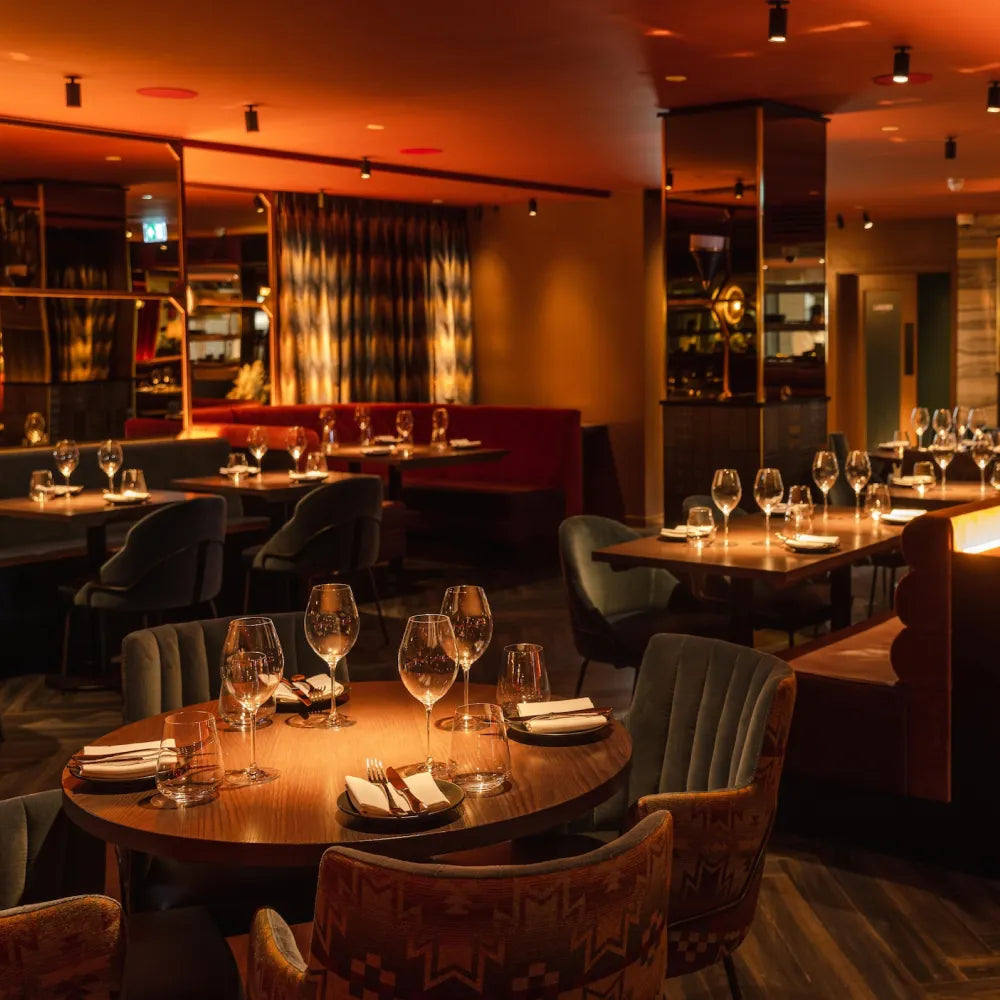 Gaucho, UK: Stylish restaurant interior with dim lighting and elegantly set tables.