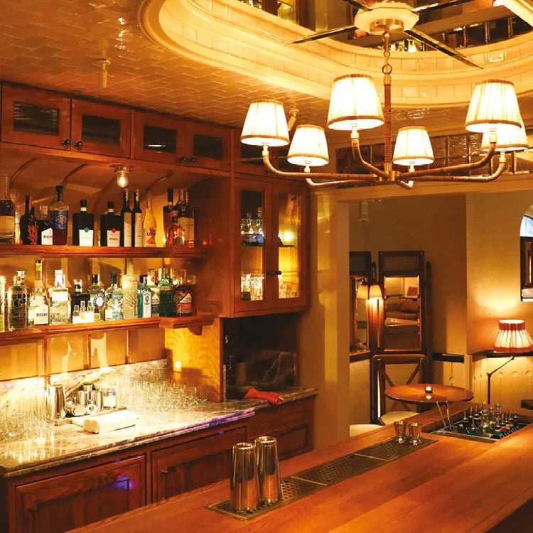 Nipperkin, London: Cosy bar interior with wooden shelves, bottles, and warm lighting.