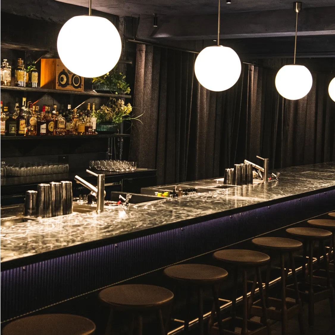 Soma, London: Dimly lit bar with stools, bottles, and hanging lights.