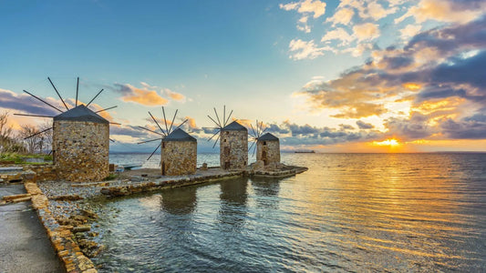 Windmills by the water at sunset with a colorful sky in Chios island in Greece