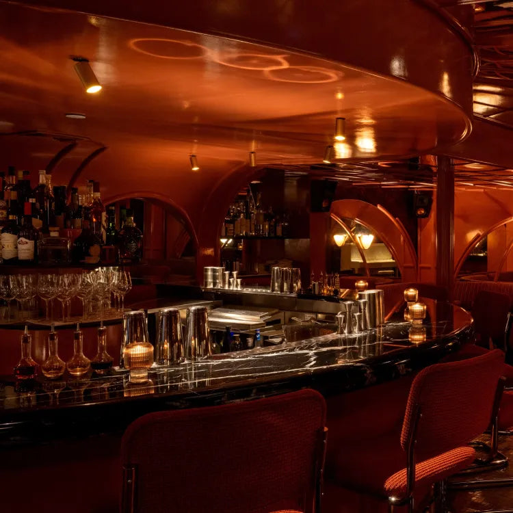 Experimental Cocktail Club Soho, London: warmly lit, upscale bar with a dark countertop and red seating