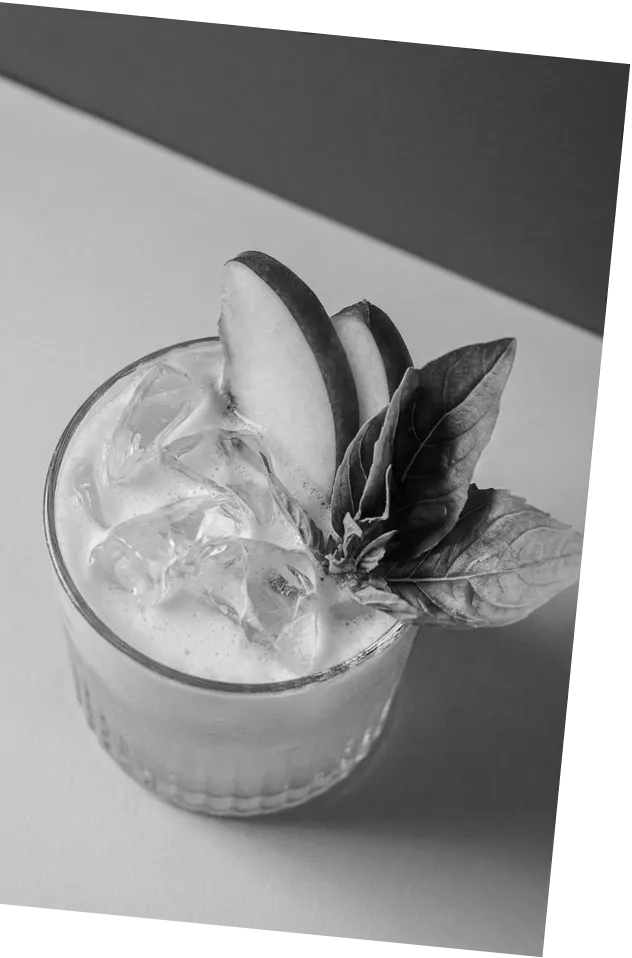 Black and white picture of an Axia Greek Mastiha Spirit Basilisk Smash Cocktail with ice, peach slices and basil