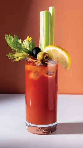 Axia Greek Mastiha Spirit Bloody Medusa Cocktail with garnishes on a gradient orange background