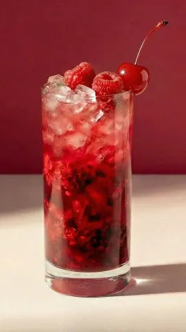 Axia Greek Mastiha Spirit Bramble Cocktail with ice, raspberries, and a cherry on a red background