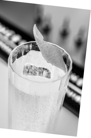 Black and white picture of an Axia Greek Mastiha Spirit and London Essence Lemonade Collins Cocktail on a bar