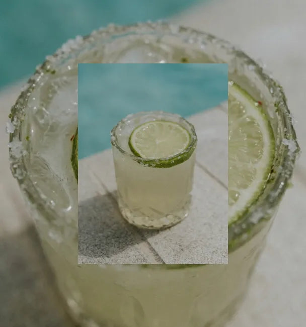 Axia Greek Mastiha Spirit Margarita Cocktail with a lime wedge, ice cubes and salt next to a swimming pool with a secondary picture in the background of another Margarita cocktail