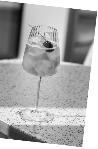 Black and white picture of an Axia Greek Mastiha Spirit and red wine Heliodoro Cocktail with Joia Battersea on a table