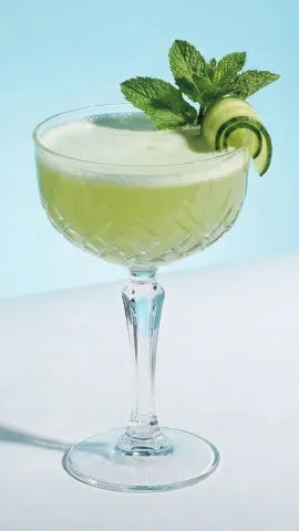 Axia Greek Mastiha Spirit Southside Cocktail with cucumber and mint leaves on a light blue background