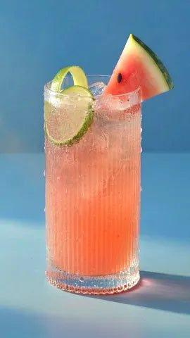 Axia Mastiha Spirit Cocktail with watermelon and line granish on a blue background