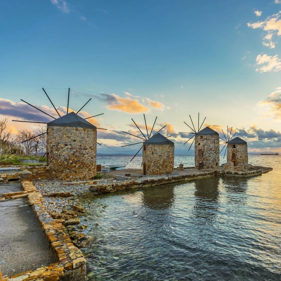 Windmills by the water at sunset with a colorful sky in Chios island in Greece