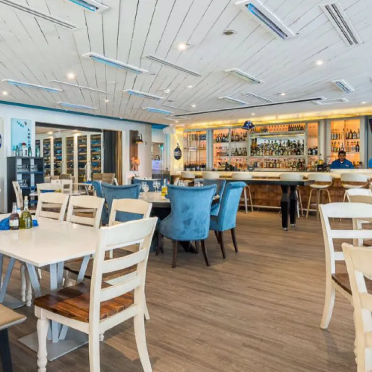 Santorini by Georgios, Miami: bright and modern restaurant dining area with tables, chairs, and a bar in the background