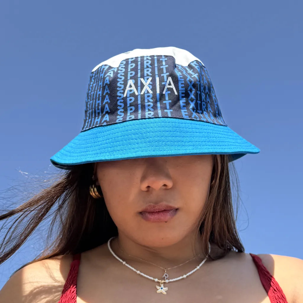 Axia Extra Dry Mastiha Spirit branded Bucket Hat worn by a woman with blue sky behind