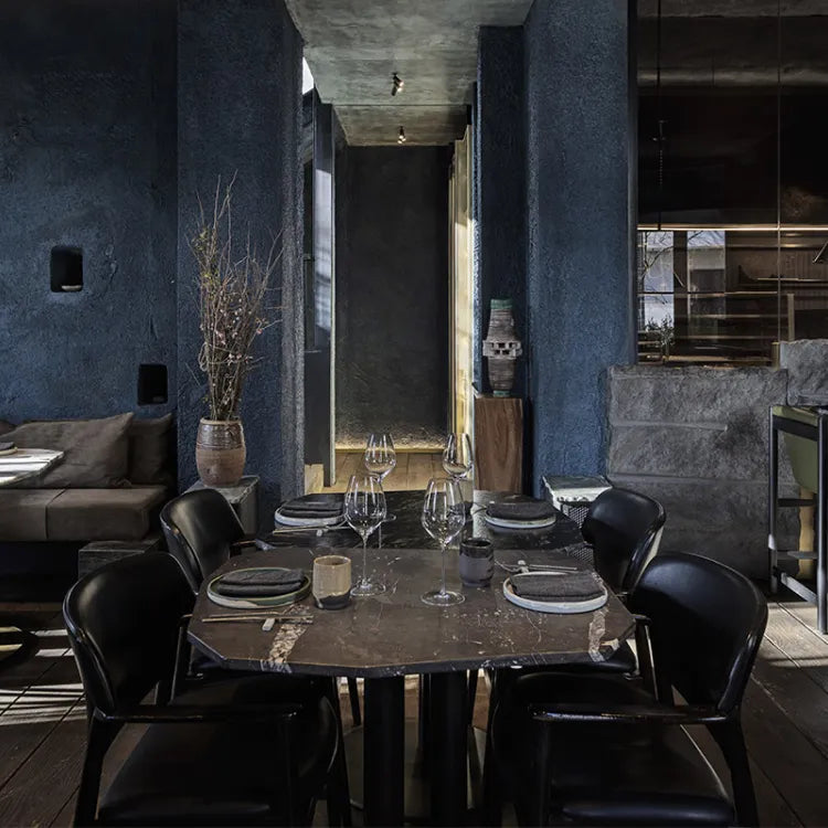 Humains Restaurant, Athens: Modern dining room with dark walls, a marble table, and black chairs.