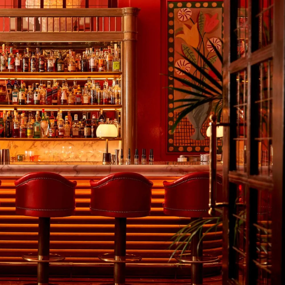 The Coral Room, London: luxurious red bar with leather stools and a well-stocked alcohol shelf
