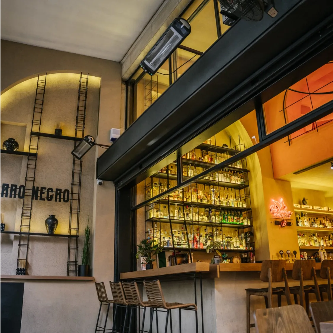 Barro Negro, Athens: Cosy bar interior with well-stocked shelves and warm lighting.