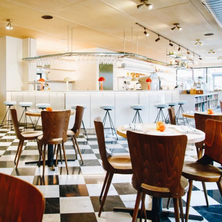 Modern café interior with wooden chairs, round tables, and checkered floor from Pecoraro Latteria in Brooklyn, New York