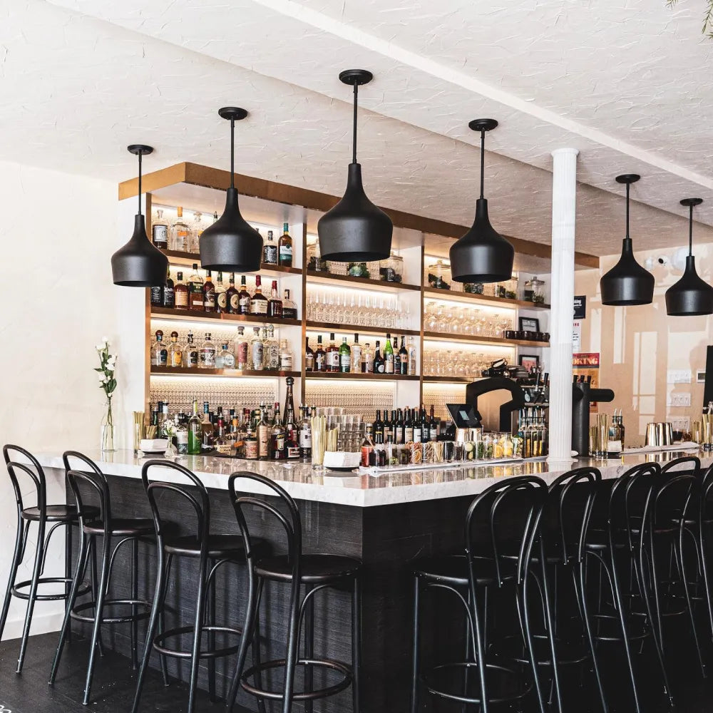 Terasa North Ninth, New York: Modern bar interior with a marble counter, black chairs, and pendant lighting.