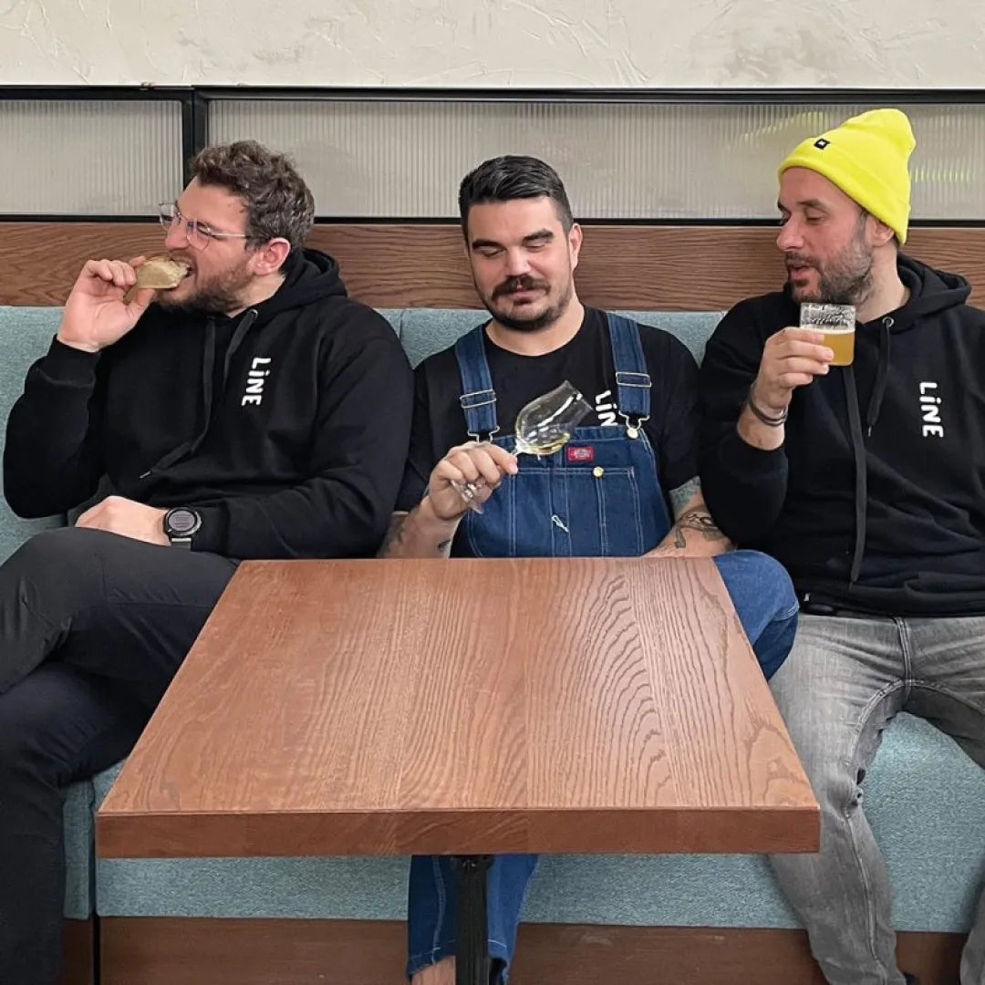 Three men sitting on a sofa at a table while drinking